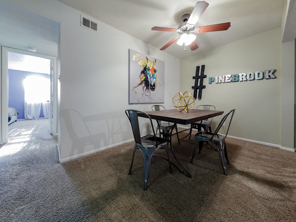 a dining area with a table and chairs and a ceiling fan