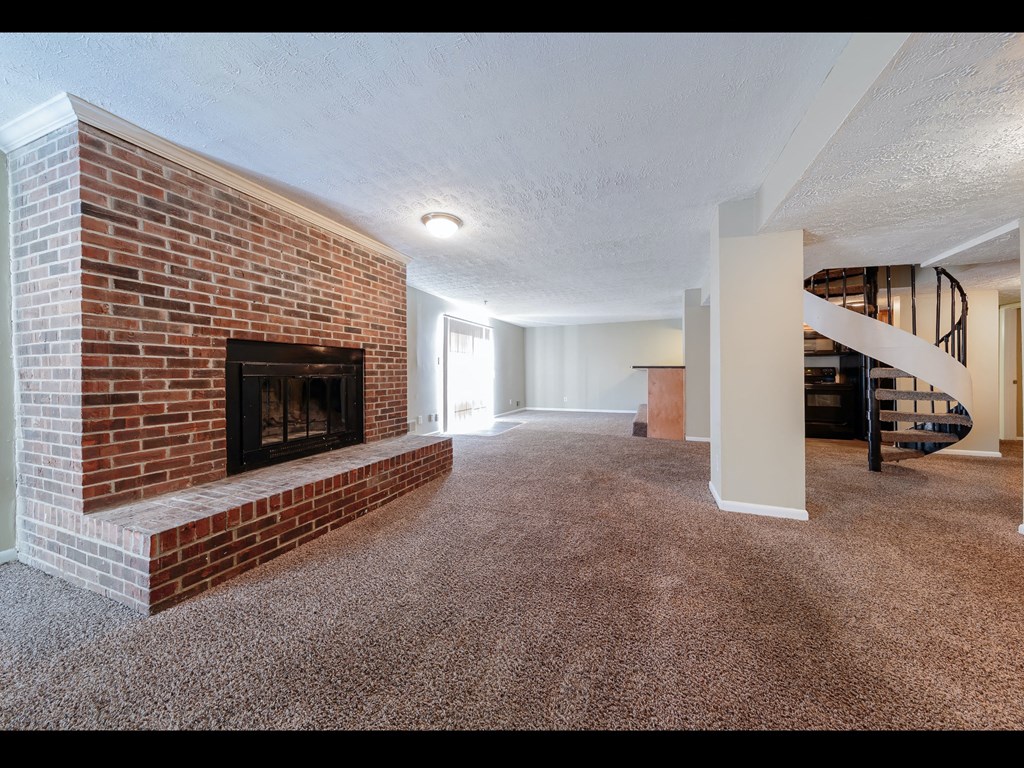 a large living room with a brick fireplace and carpeted flooring