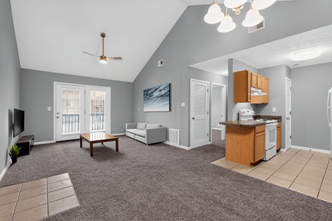 A spacious living room with a grey carpet and a ceiling fan.