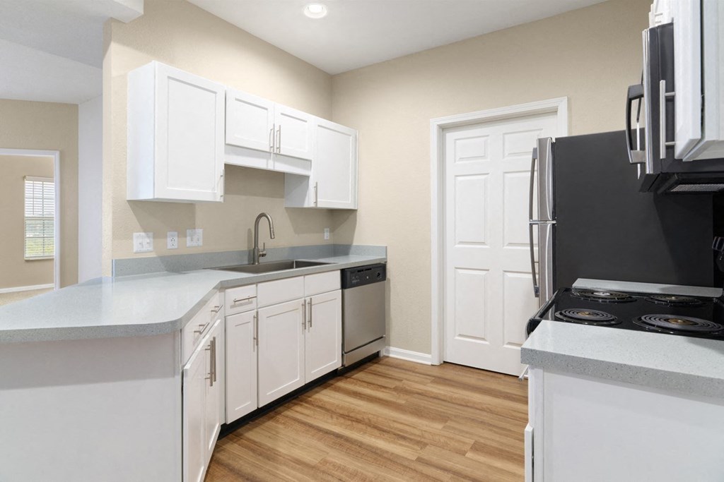 an empty kitchen with white cabinets and a black refrigerator