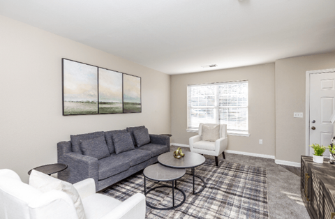 A living room with a grey couch, a coffee table, and a painting on the wall.
