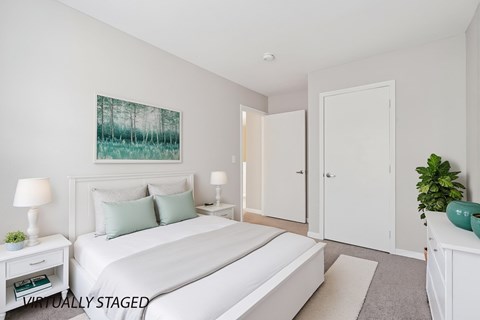 A bedroom with a large bed, two lamps, and a painting on the wall.