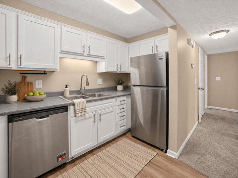 A kitchen with white cabinets and a stainless steel refrigerator.
