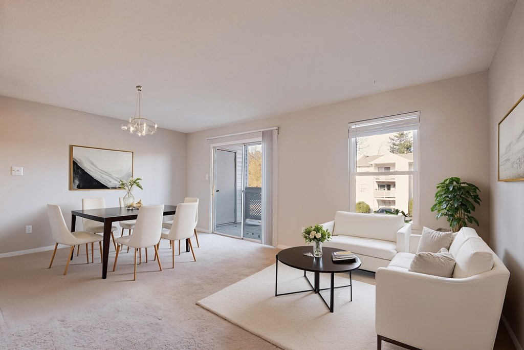 A living room with a white couch, a dining table with chairs, and a chandelier.