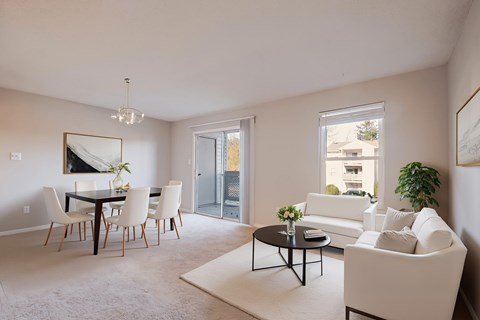 A living room with a white couch, a dining table with chairs, and a chandelier.