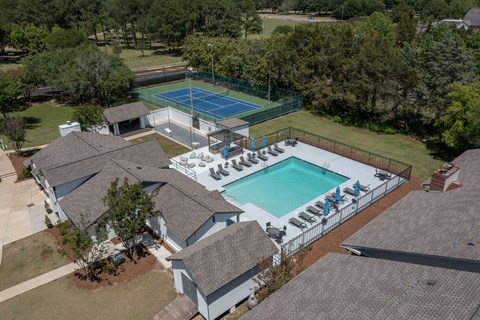 a birdseye view of a pool and a house with a tennis court