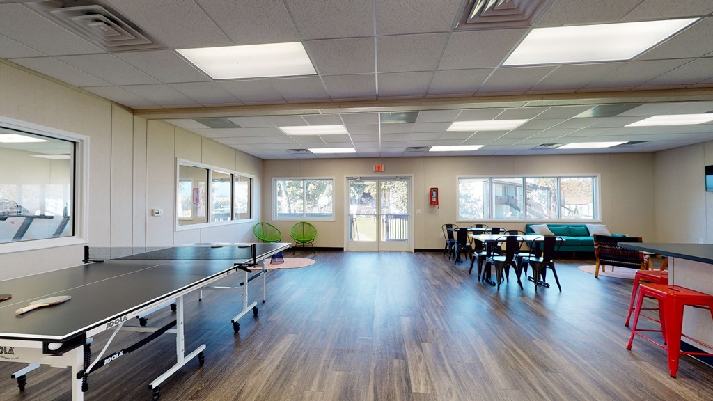 a recreation room with ping pong tables and chairs