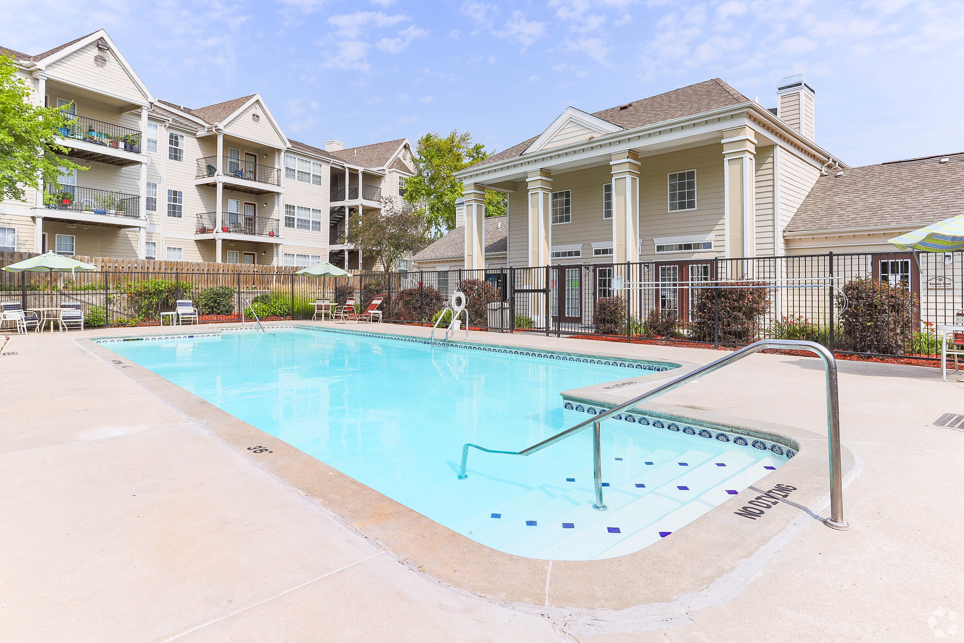 Sparkling outdoor swimming pool with white fence surround at Waterbrook Apartments in Lincoln, Nebraska, professionally operated by Highlands Vista Group.
