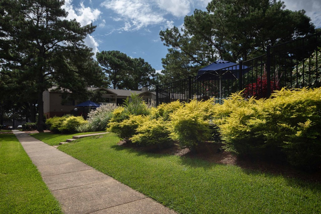 a sidewalk leading to a building with a black fence