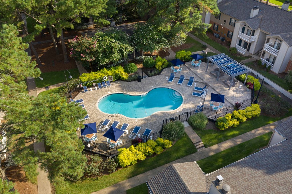 an aerial view of a resort style pool with lounge chairs and umbrellas
