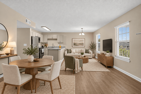 A well-lit, spacious kitchen and living room with a dining table and chairs.
