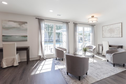 A living room with a grey sofa, a white chair, and a painting on the wall.