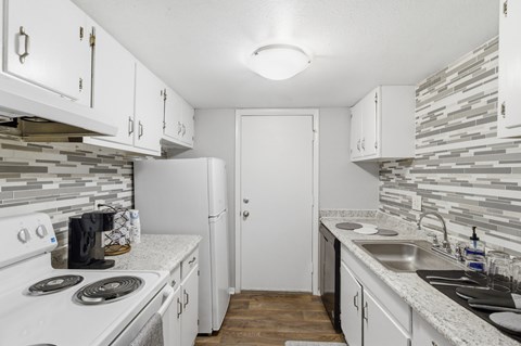 A kitchen with white cabinets and a white stove top oven.