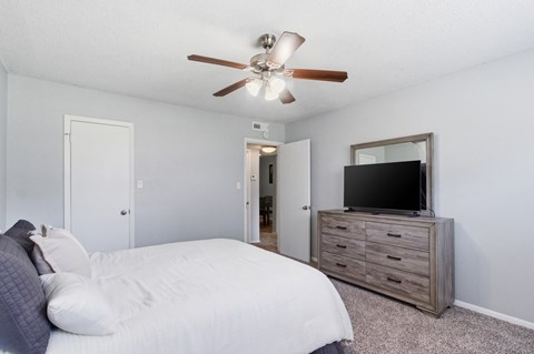 A furnished apartment bedroom at Aspen Run Apartments in Tallahassee, Florida, featuring a bed, dresser, and television.