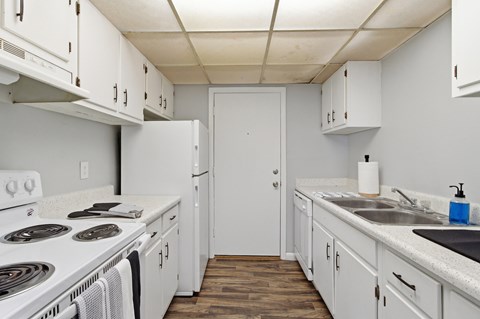 A kitchen with white cabinets and a white door.