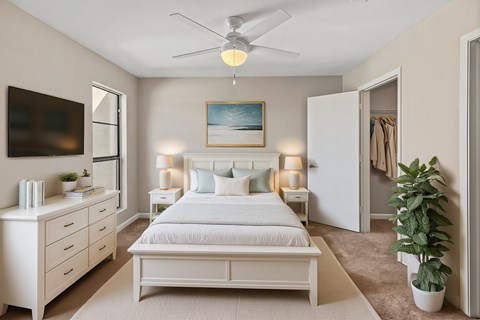 A bedroom with a bed, dresser, and ceiling fan.