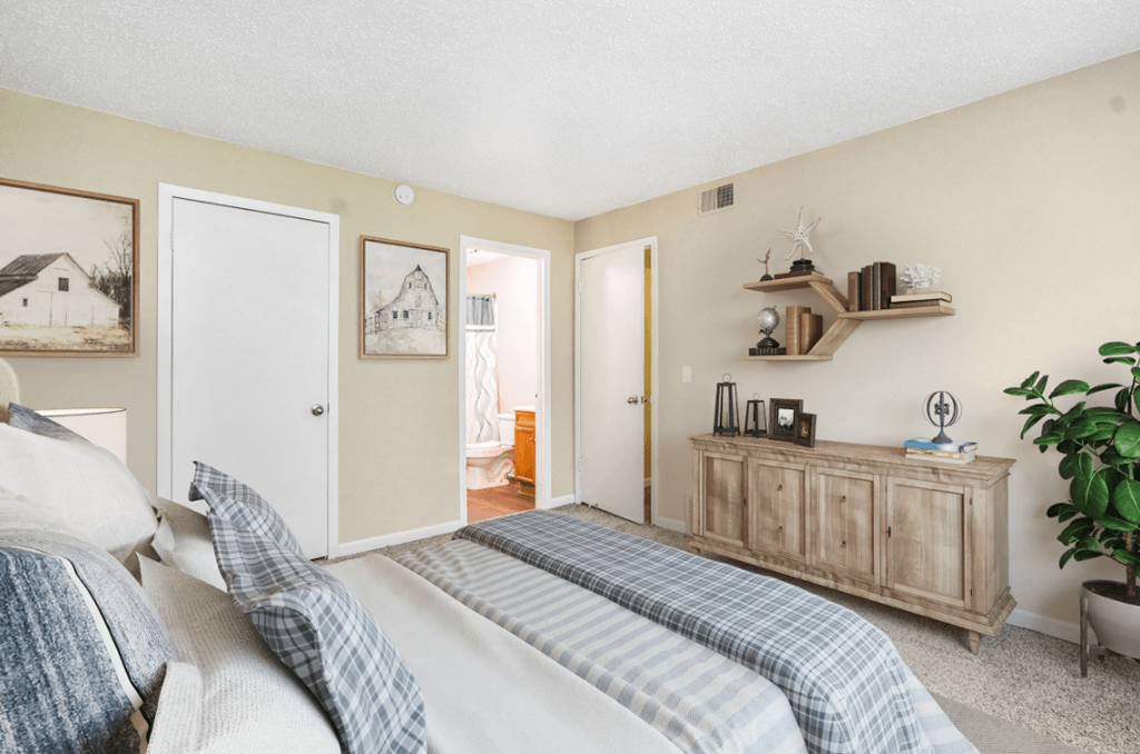 A bedroom with a bed, a dresser, and a plant.