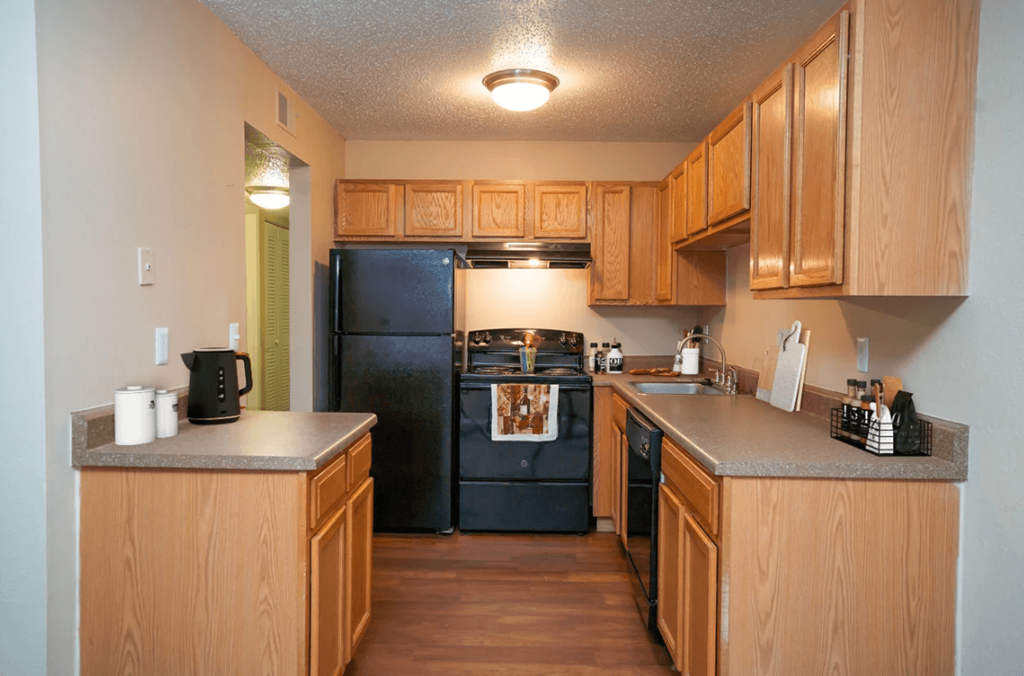 A kitchen with wooden cabinets and a black fridge.