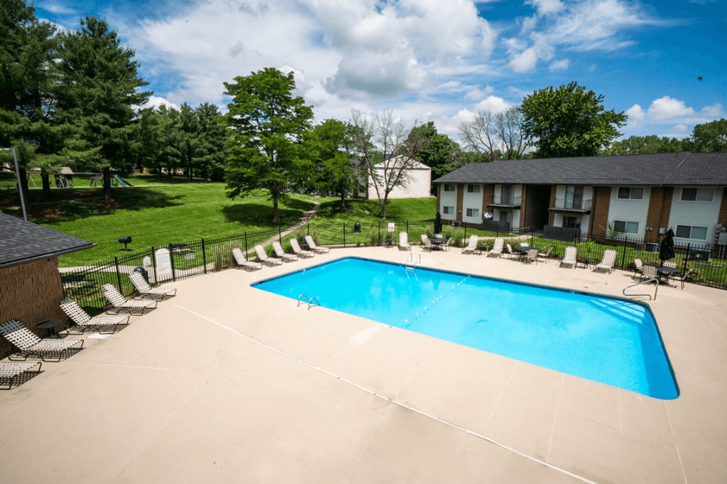A large outdoor swimming pool surrounded by lounge chairs and trees.