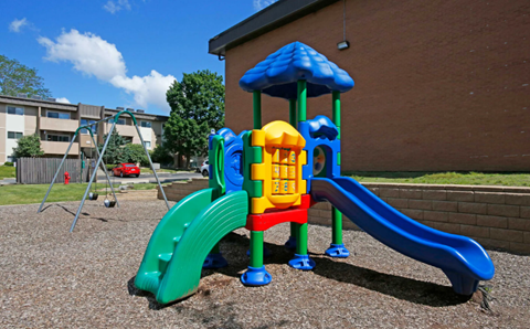 A playground with a blue slide and a yellow and red structure.