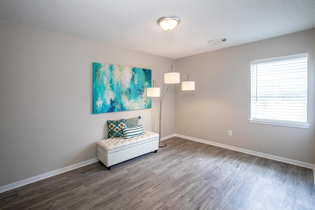 an empty living room with a lamp and a painting on the wall