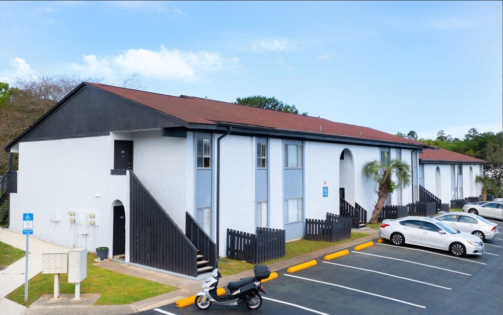 a white building with a red roof and cars in a parking lot