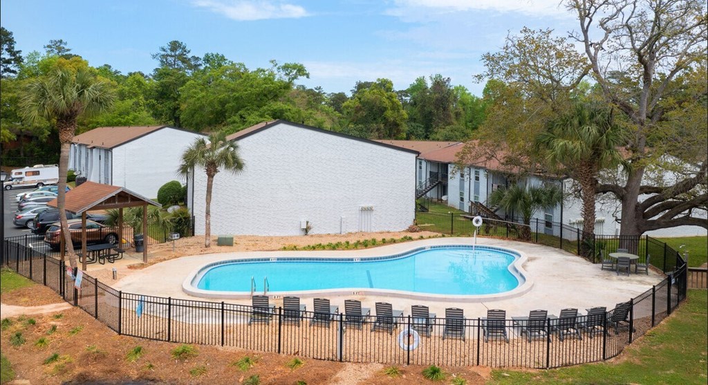a swimming pool with chairs around it in front of a house
