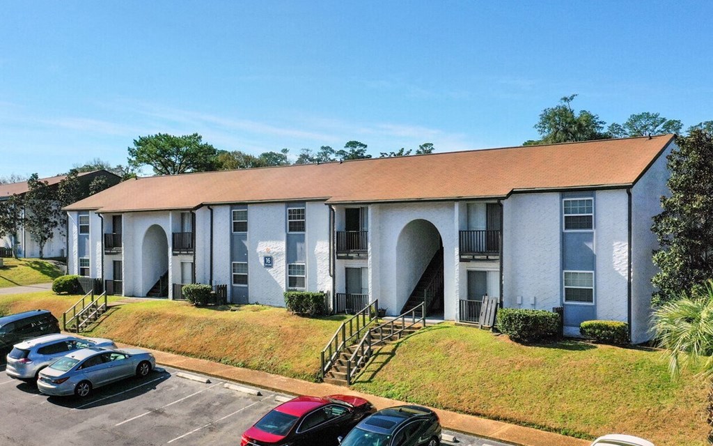 an apartment building with cars parked in a parking lot
