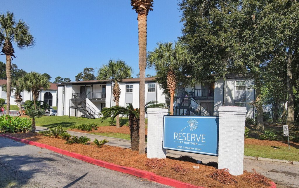 a blue reserve sign in front of a building with palm trees