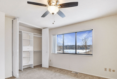 A room with a ceiling fan and a large window overlooking a snowy landscape.
