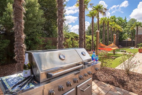 a barbecue grill in a backyard with palm trees