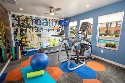 a gym with exercise equipment and a wall of graffiti