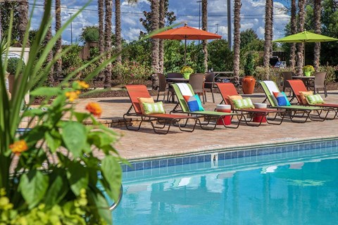 a swimming pool with lawn chairs and umbrellas next to a pool