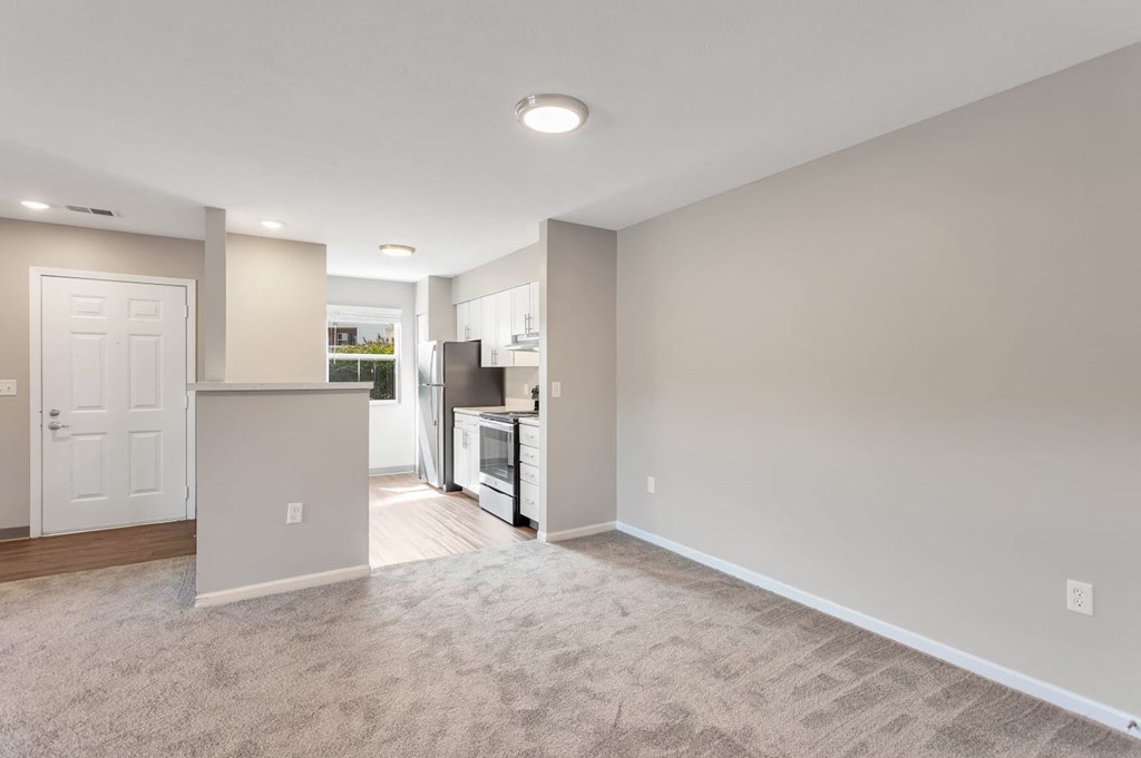 an empty living room and kitchen with a white door