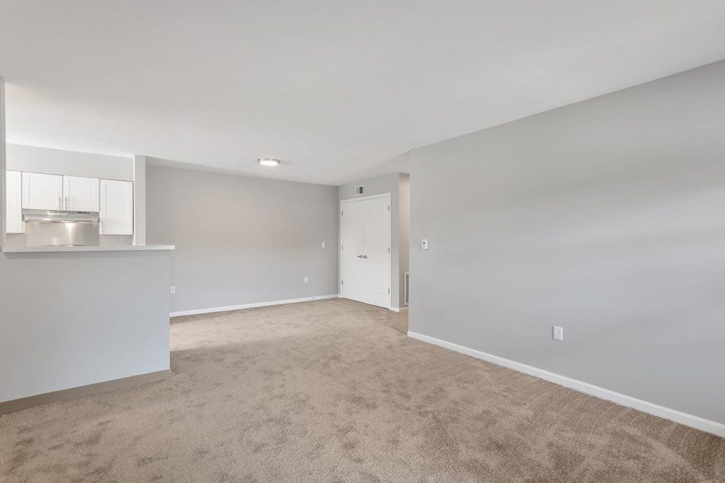the living room and kitchen of an empty home with carpeting
