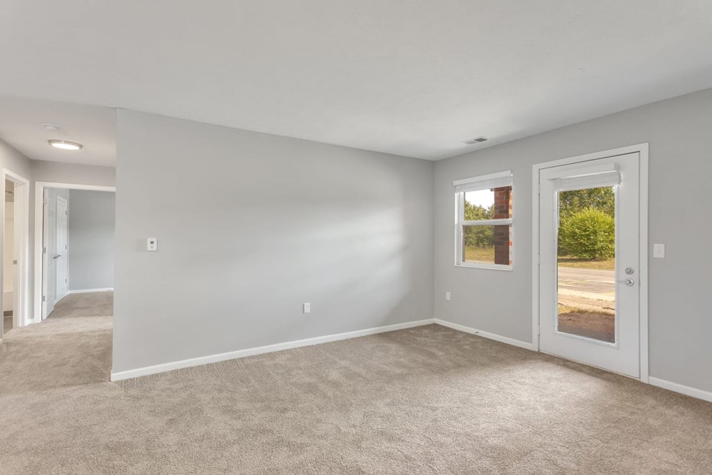 a living room with white walls and a carpeted floor