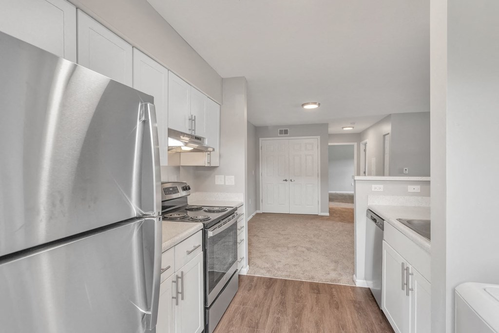 the kitchen and living room of a house with white cabinets and stainless steel appliances
