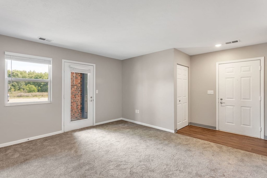 an empty living room with two doors and a window