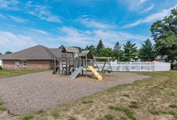 a playground with a swing set in front of a house