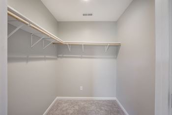a large empty closet in a home with white walls and a carpet