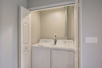 a white laundry room with two sinks and a washer and dryer