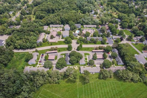 an aerial view of a park with houses and trees and a tennis court