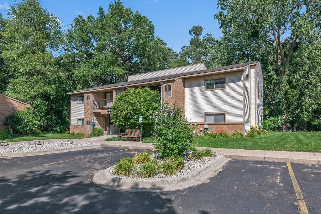 the front of a house with a parking lot and trees