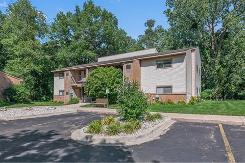 the front of a house with a parking lot and trees