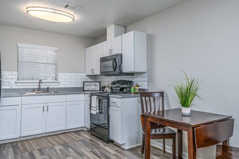 a kitchen with white cabinets and a table with a chair