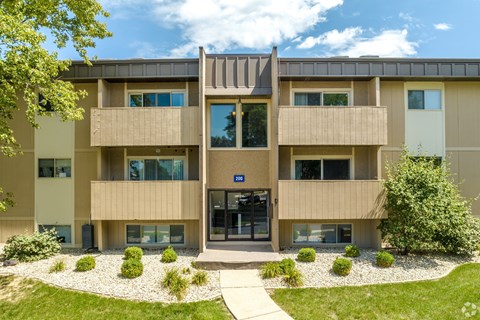 A modern building with a central entrance and a gravel area in front.