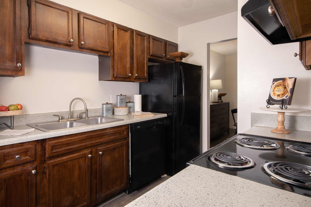 a kitchen with a black refrigerator freezer next to a stove top oven