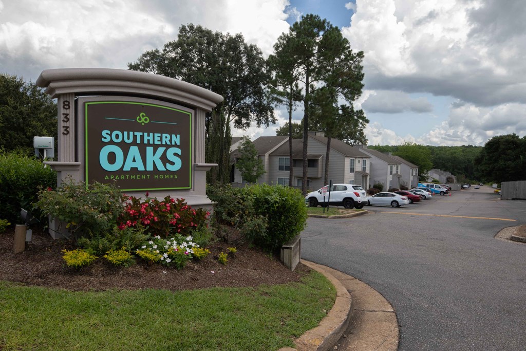 a sign for southern oaks apartments with a parking lot in the background