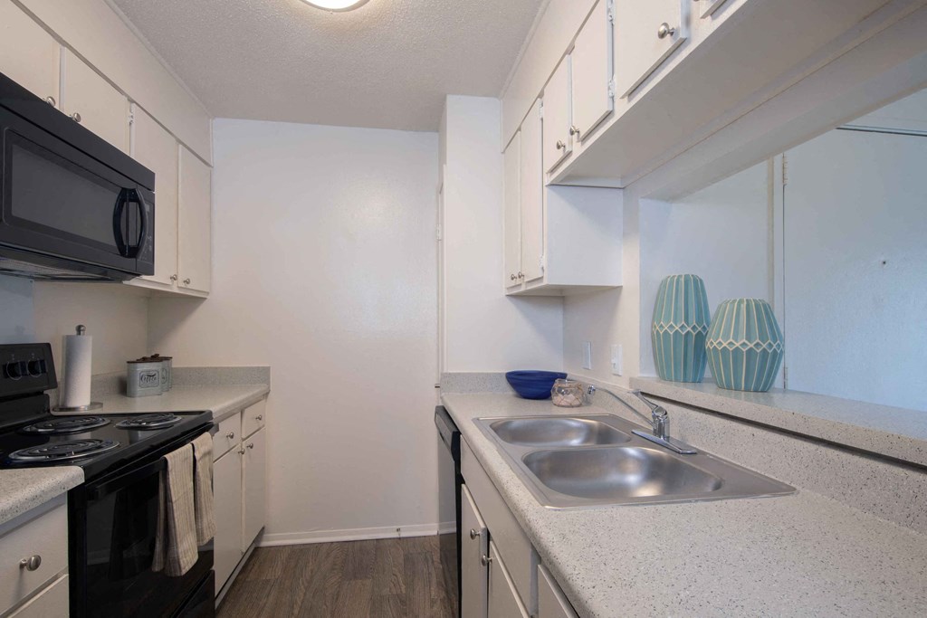a kitchen with white cabinets and black appliances