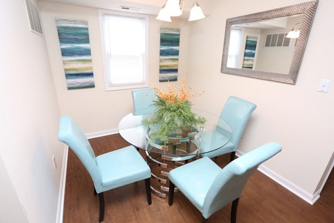 A dining room with a glass table and four chairs.